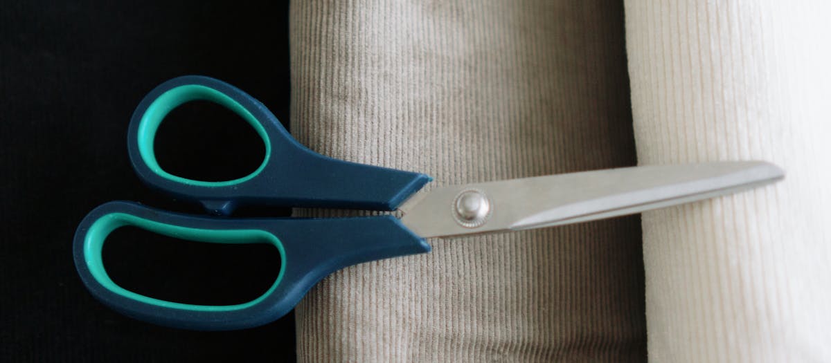 Blue-handled scissors resting on a mix of black and white fabrics.