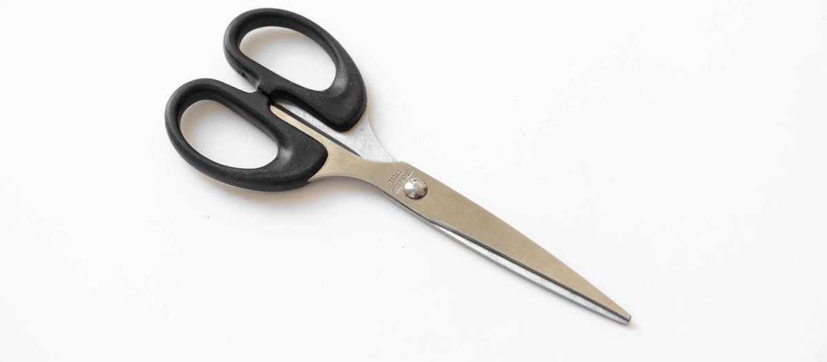 Close-up of stainless steel scissors with black handles on a white background, perfect stationery tool.